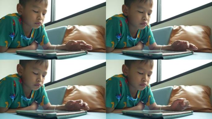亚洲男孩不由自主地躺在平板电脑上。