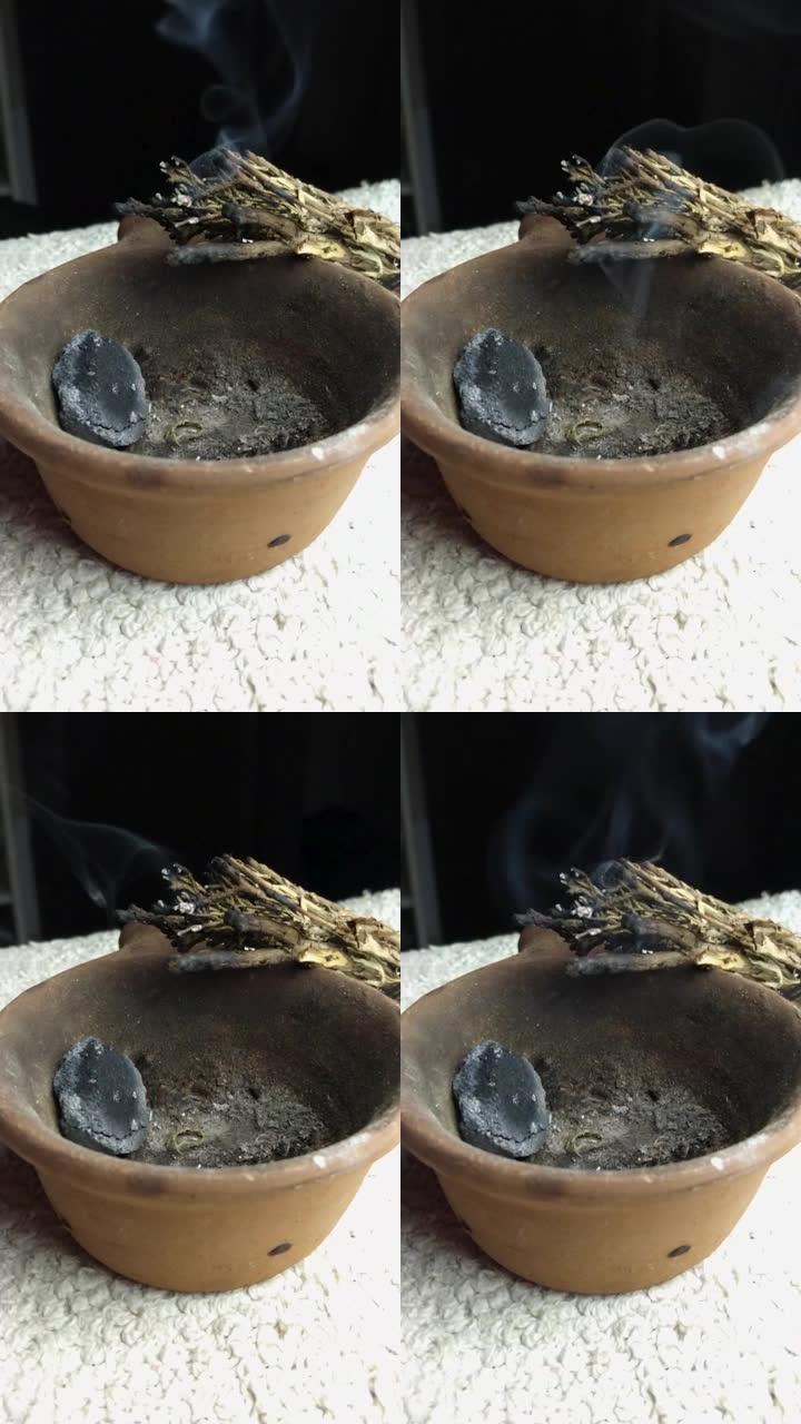 在黑色背景的桌子上的碗中燃烧鼠尾草，显示鼠尾草烟雾
