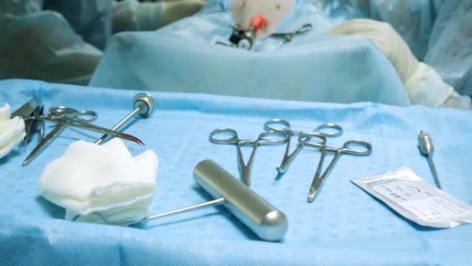 手术器械放在桌子上，上面覆盖着蓝色的无菌布。在后台，操作团队进行内窥镜手术。医学和医疗保健的概念。