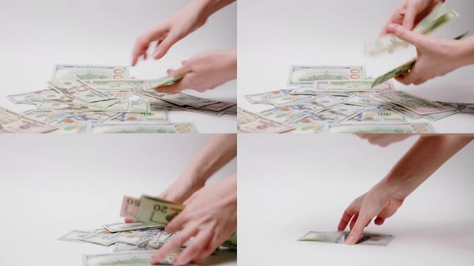金钱和投资。女性手收集散布在白色背景上的美元。特写。贿赂和腐败的概念