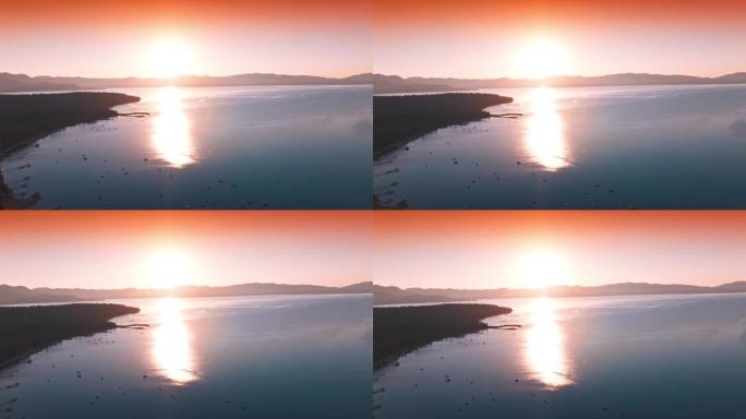 湖上惊人的粉红色日落。太阳反射在光滑的水面上。水上多艘船。
