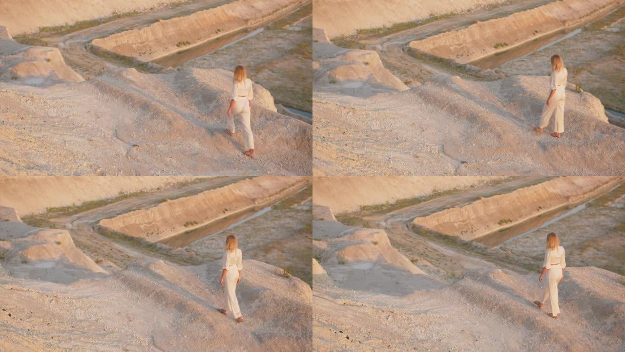 一个穿着白色西装的女人走近山的边缘
