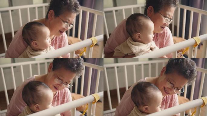 幸福的家庭开朗的亚洲高级女人祖母抱着和可爱的小婴儿蹒跚学步的孙女一起笑，一起拥抱爱，坐在家里的室内房