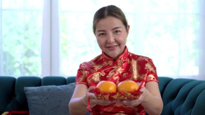 亚洲年轻女子穿旗袍在农历新年处理橘子