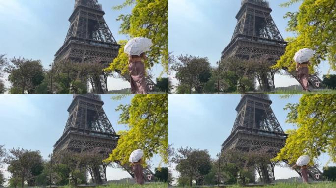 一个穿着长裙的女孩带着镂空的雨伞去埃菲尔铁塔，背对着相机，可以用于室内广告文字非常漂亮的慢动作视频