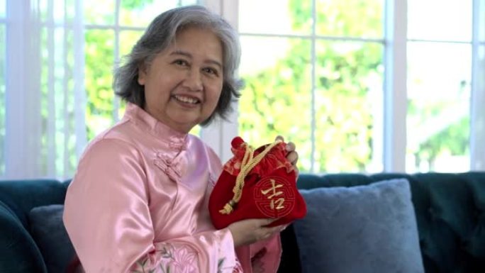 亚洲高级妇女在农历新年展示幸运的红色包