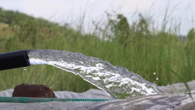 在印度农村，pvc管将水泵入绿色领域的4k视图灌溉用水从管道到运河用于农业领域。淡水在管井附近流动。