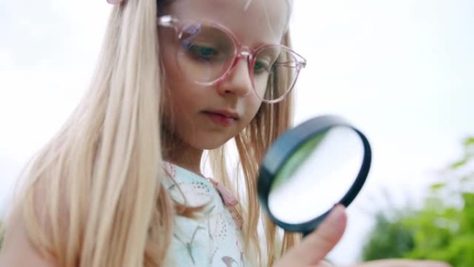 可爱的好奇女孩与放大镜在大自然。