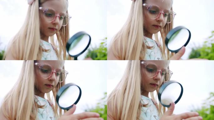 可爱的好奇女孩与放大镜在大自然。