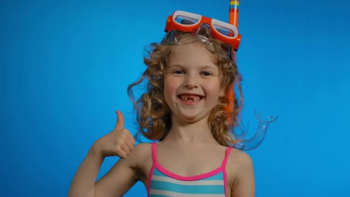 戴着游泳面具和通气管的可爱的卷发女孩露出大拇指