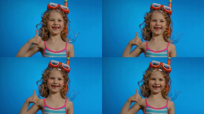 戴着游泳面具和通气管的可爱的卷发女孩露出大拇指