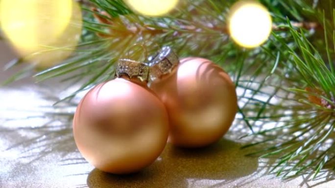 节日装饰的圣诞树树枝，在模糊的闪闪发光的童话背景上有明亮的金色球。花环灯，波克效应。圣诞节和节日快乐