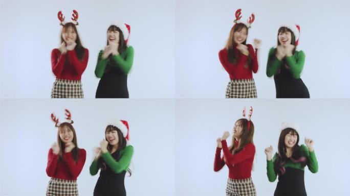 两个快乐的亚洲女性在圣诞节概念跳舞，在白色背景工作室里表现得很有趣。新年快乐假期