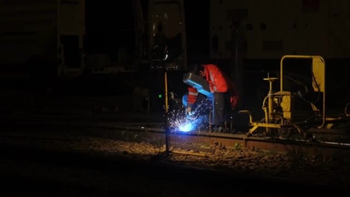专业熟练的焊工夜间使用氧燃料焊炬固定电车轨道