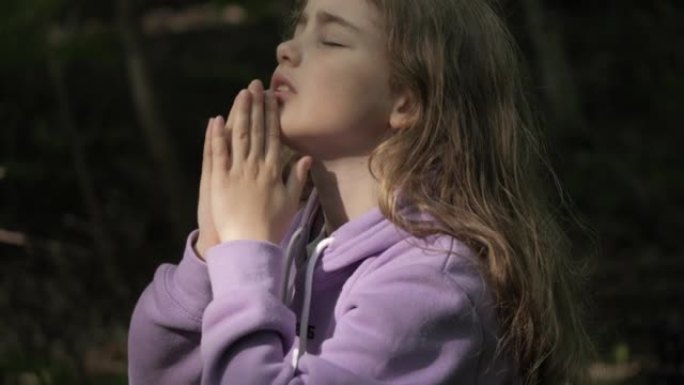 宗教。小女孩在户外祈祷时双手合十，向上帝祈祷。忧心忡忡的少女寻找希望和信仰向上帝祈祷。心中充满希望的