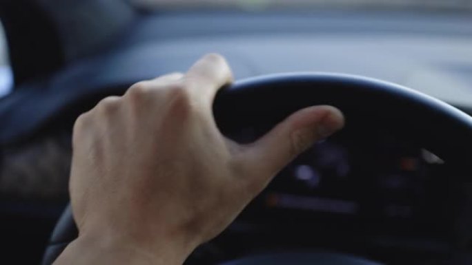 男子开车时将手放在车辆方向盘上的特写镜头。男性在高速公路上驾驶汽车，手在车轮上移动。面目全非的商人把