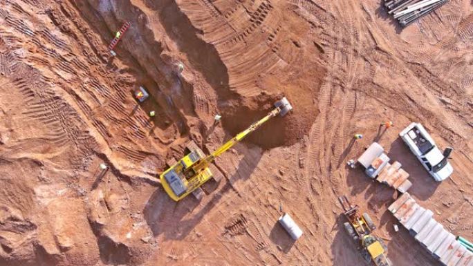 挖掘机挖了一个坑，用于下水道连接和在建筑工地上铺设地下雨水管道。