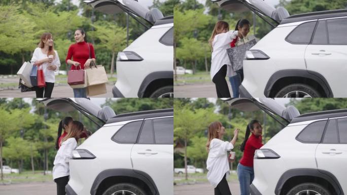 两名亚洲女性在停车场互相有趣地交谈，走向自己的车。他们携带许多购物袋，并将其装在汽车后备箱中。