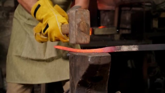 两个铁匠在一个古老的铁砧上敲打铁锤。