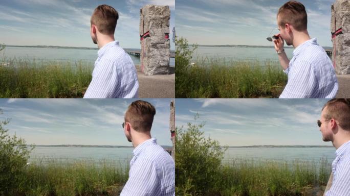 年轻的德国男性坐在康斯坦茨湖上的海岸上，向远处望去