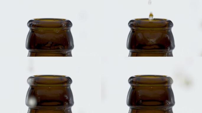 啤酒滴在白色背景下打开后掉落的瓶颈特写。