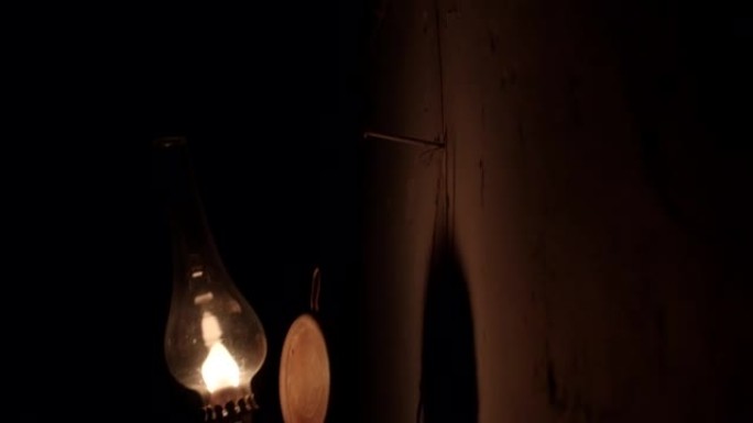 老妇人把煤油灯挂在墙上。