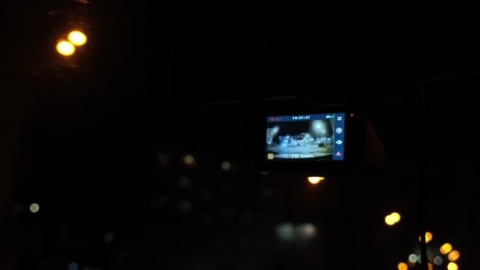 数字录像机在车里工作。汽车在夜城移动。大城市的夜灯