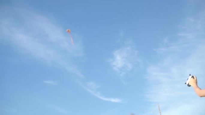 4k小女孩在明亮的蓝色天空中发起放风筝，拉着长绳。童年，户外消磨时间，休闲活动，游戏概念。