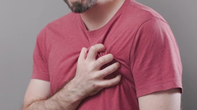 一个留着胡须的秃头男人用手抓住他的胸部，剧烈疼痛。肺部疾病。特写。心脏病发作的概念