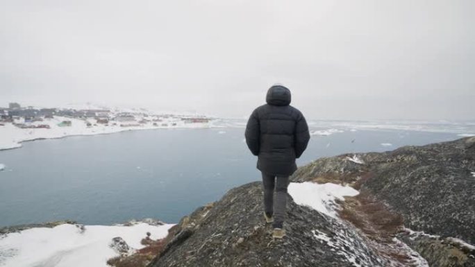 一名男子在雪山上小心翼翼地徒步旅行的中景