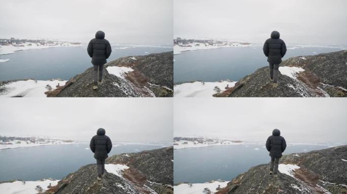 一名男子在雪山上小心翼翼地徒步旅行的中景