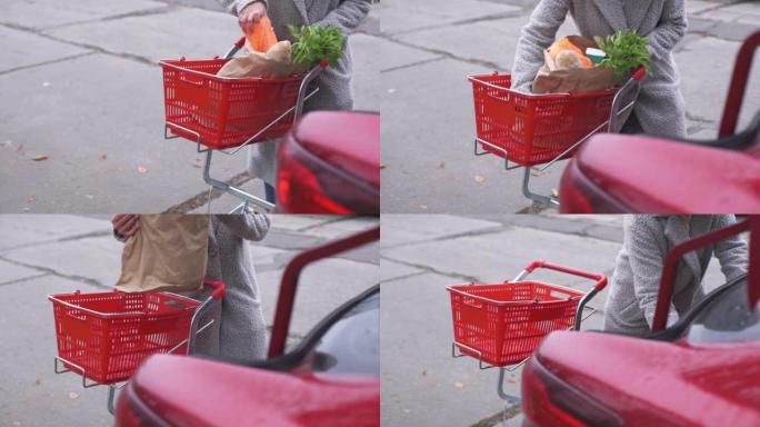 一个女人把杂货放在车里。超市里有杂货的手推车。