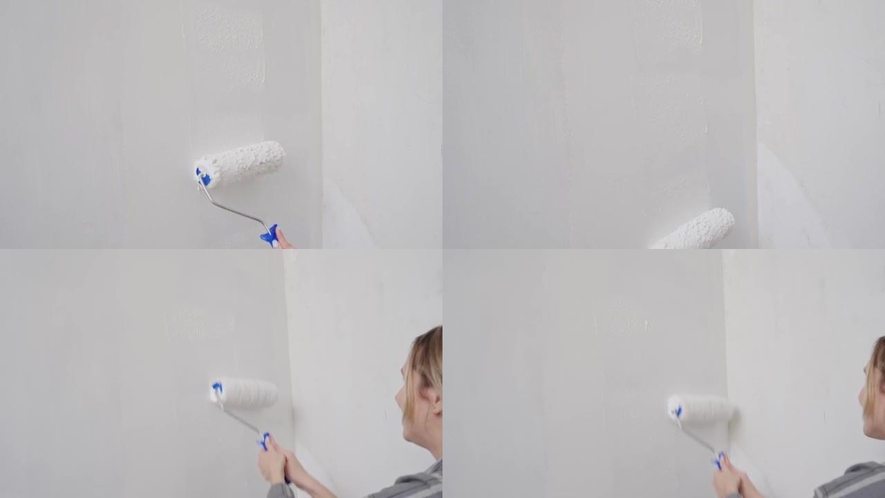 女性手的特写镜头驱动墙壁上带有白色油漆的油漆滚筒。修理，墙面粉刷