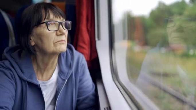 戴着眼镜的老年妇女乘火车看着窗外，玻璃反射