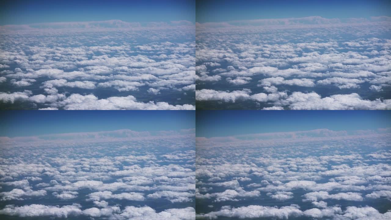 在阳光明媚的天空中，飞机飞过浮肿的云层的乘客视野