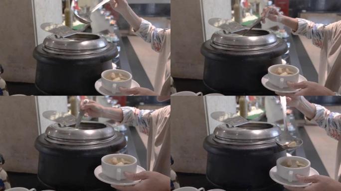 一个女人从锅到碗舀汤的特写镜头