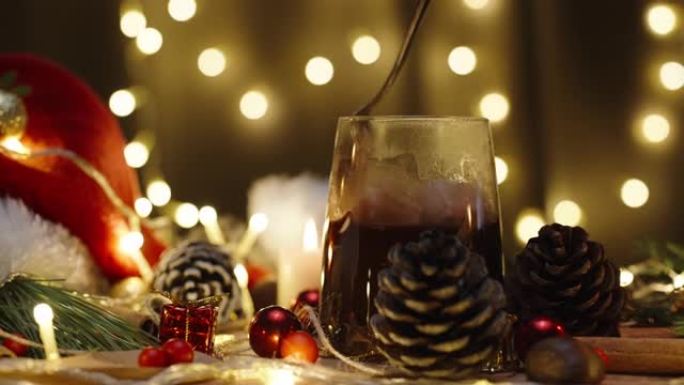 我在可可中搅拌棉花糖，在灯花环的背景下搅拌热巧克力。配有蜡烛和装饰品的圣诞餐桌。慢动作。
