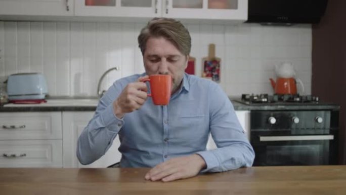 一个满意的人在厨房里喝茶、咖啡的肖像。