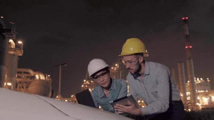 两位石油炼油厂工程师使用具有未来现实技术的数字平板电脑在夜间检查石化厂