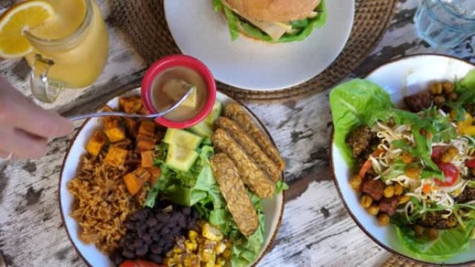 餐馆素食餐的俯视图。将鳄梨浸入酱汁中。一顿适当的早餐对你一天的健康至关重要。特写。素食者餐桌上有各种