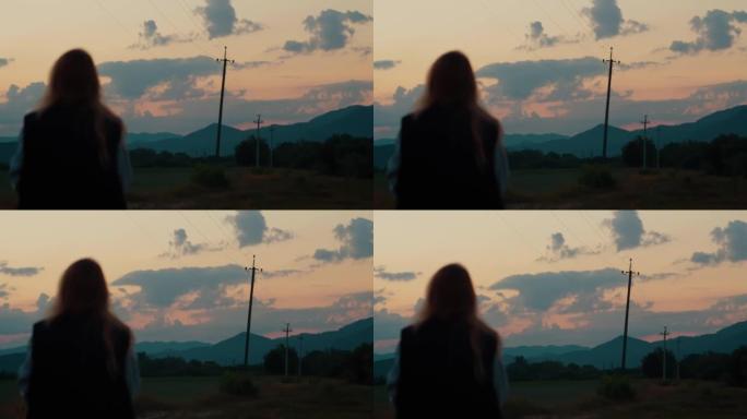 乡村女孩，穿着背心的女人在山中观看日落，俯瞰高山