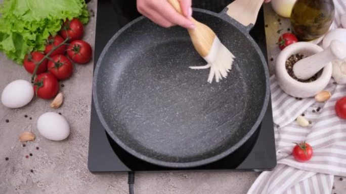 女人用硅胶刷在热煎锅上撒黄油