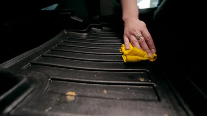 汽车清洁。一个女人的手擦拭汽车垫子上洒的咖啡。擦拭汽车脚垫上的液体。