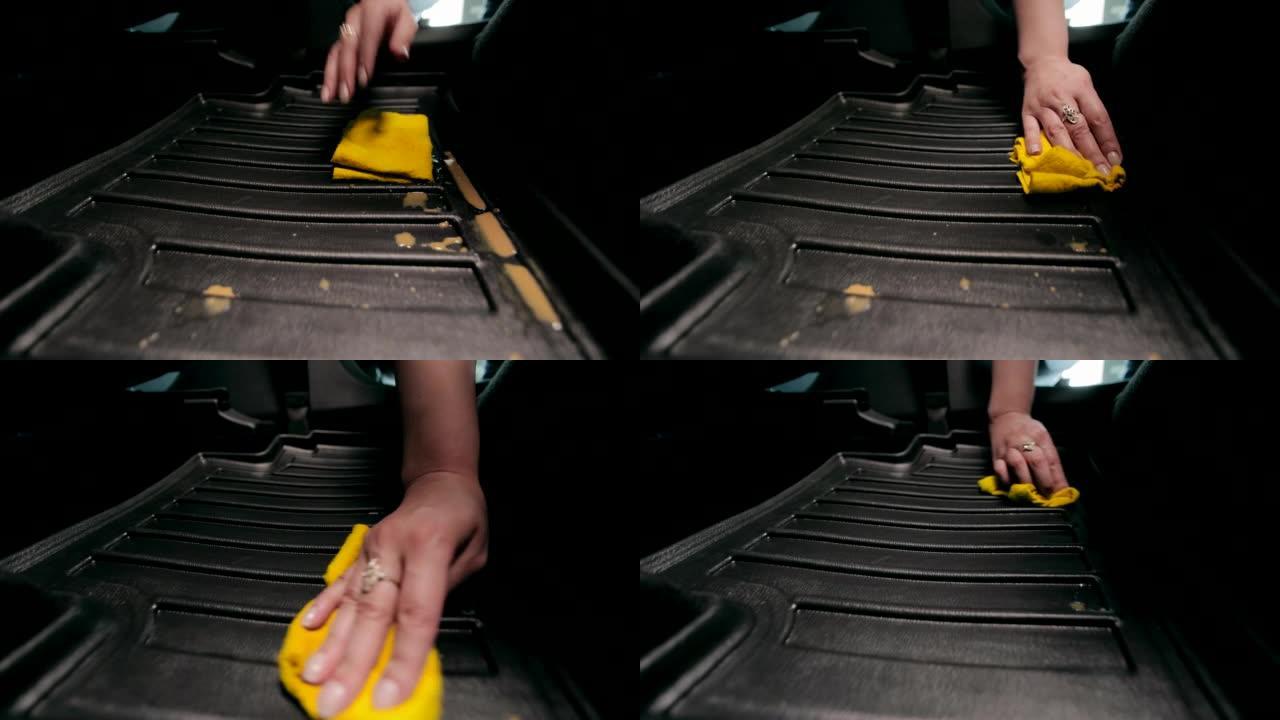汽车清洁。一个女人的手擦拭汽车垫子上洒的咖啡。擦拭汽车脚垫上的液体。