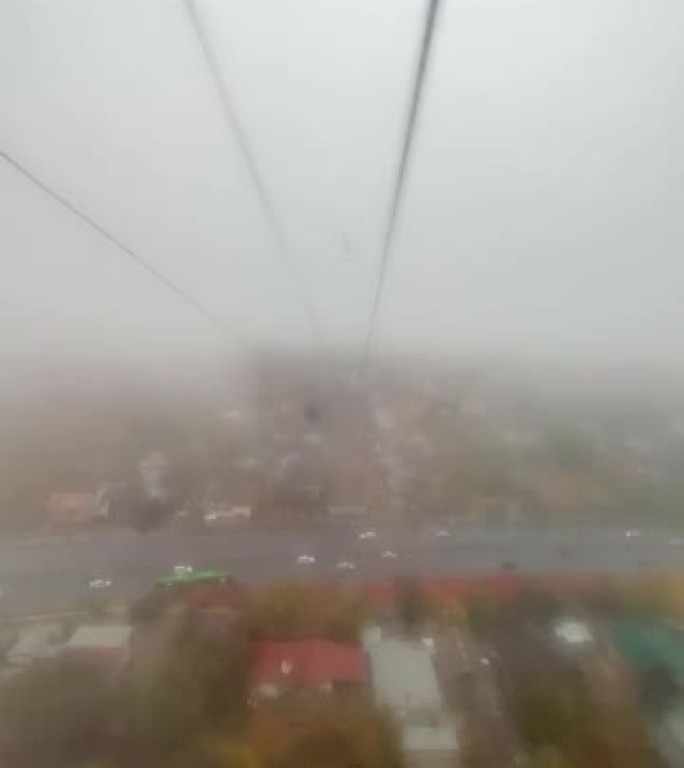 下雨，阴天的秋日，从阿斯塔纳的缆车上俯瞰城市的垂直鸟瞰图。雾蒙蒙的城市景观的俯视图，工作日城市高速公