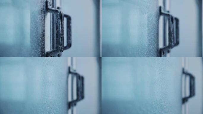 门把手上覆盖着霜。覆盖白霜的玻璃现代房屋门。瑞士阿尔卑斯山
