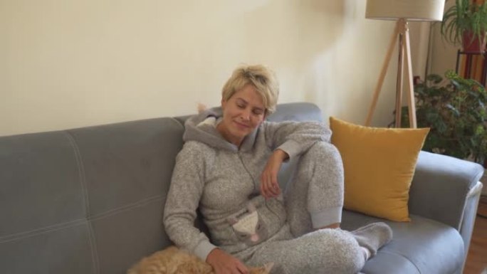 女人正穿着睡衣和被救出的猫一起坐在沙发上