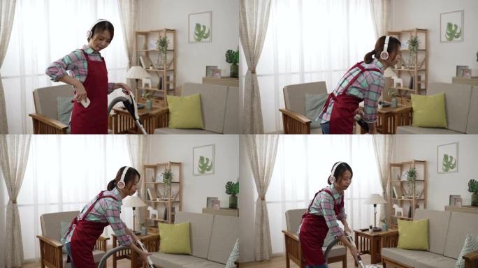 戴着耳机的年轻亚洲女性在家里舒适的房间里清洁地毯时选择音乐和跳舞。家庭主妇使用现代无绳真空吸尘器。妻