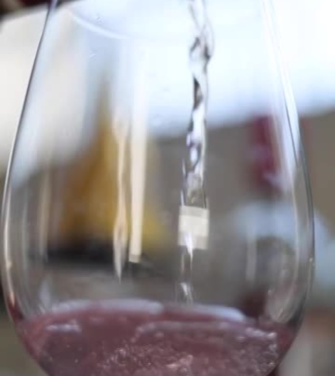 透明玻璃杯和玫瑰酒从瓶中倒入的垂直镜头
