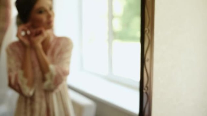戴着面纱的女孩站在粉色睡衣和缎子长袍照镜子里
